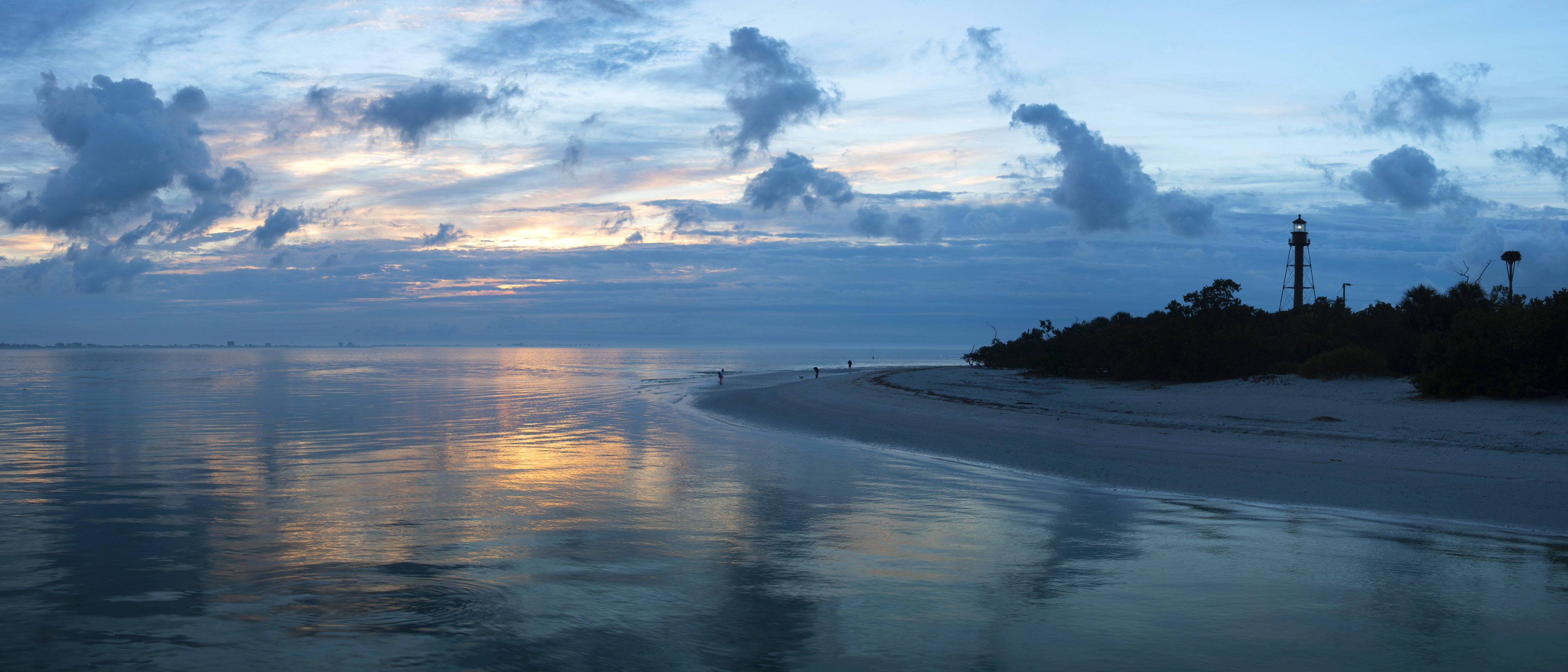 yellow and blue light during sunset over the ocean and Sanibel Island in Florida. The water is calm and serene. 