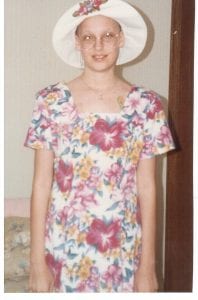 Carolyn, a childhood cancer survivor, smiles in a summer dress. 