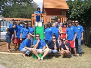 Eric Newman, the founder of Rock Solid Foundation, poses for a photo with 20 other people in front of a children's playset they just completed. 