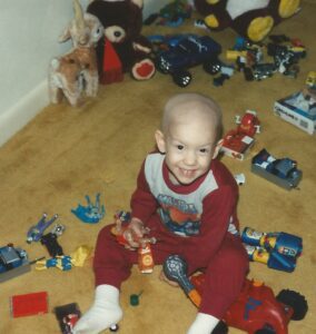 An old photo of Eric Newman, the founder of Roc Solid Foundation, shows him as a three year old sitting on the floor with a bunch of toys. 